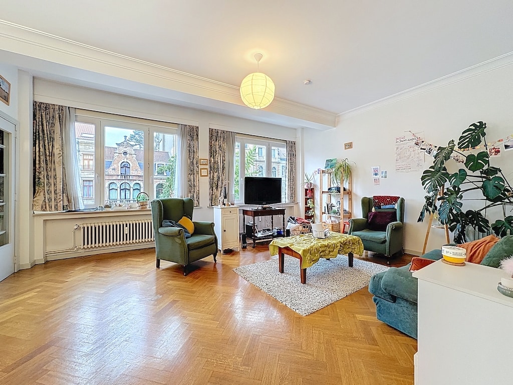 Salon moderne lumineux avec parquet en chevrons, mobilier confortable et décoration minimaliste.
