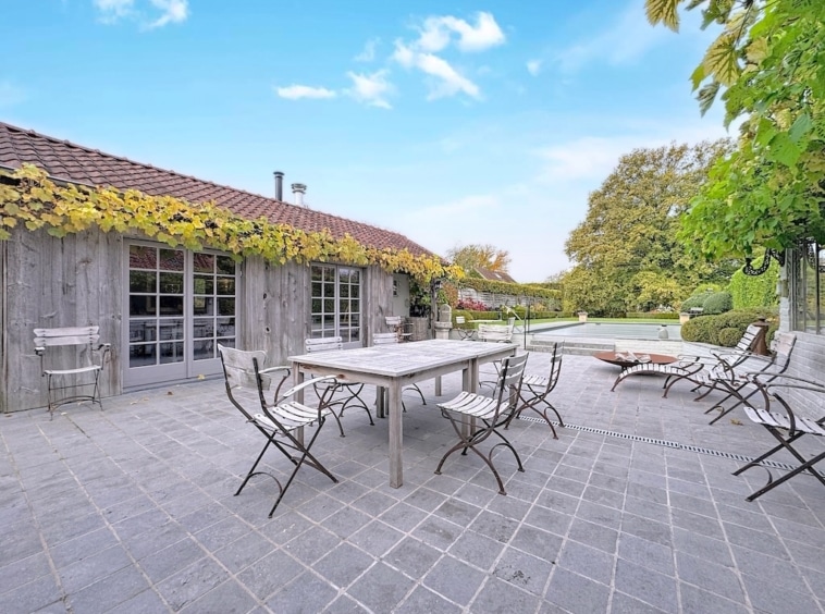 Rustieke veranda met houten meubilair, weelderige groene tuin en rustige buitenomgeving.