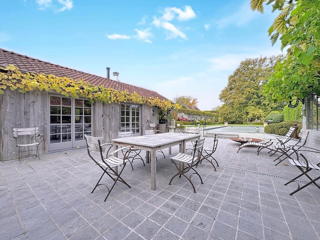 Rustieke veranda met houten meubilair, weelderige groene tuin en rustige buitenomgeving.