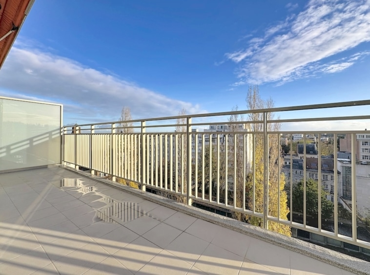 Balcon moderne avec vue urbaine, arbres automnaux, ambiance calme, lumière naturelle, espace détente.