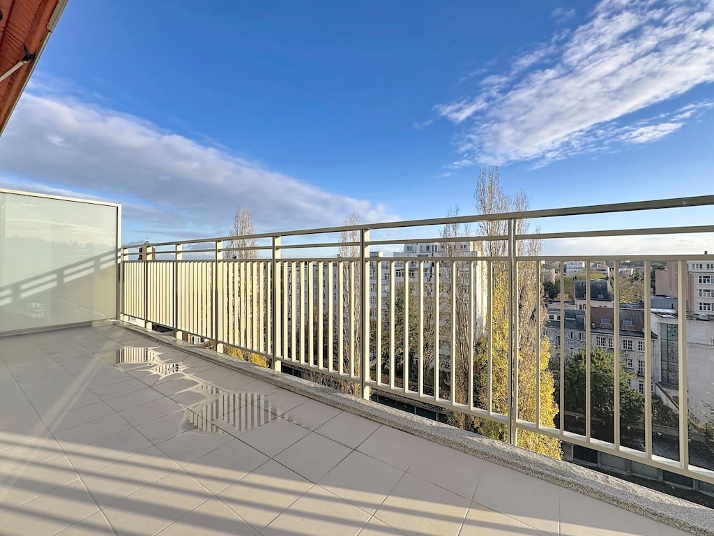 Balcon moderne avec vue urbaine, arbres automnaux, ambiance calme, lumière naturelle, espace détente.
