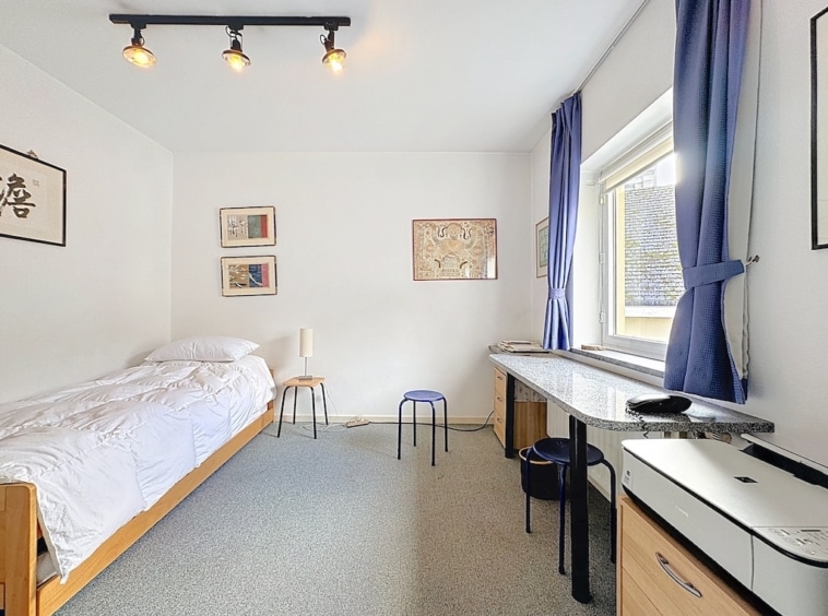 Chambre moderne, lumineuse et calme avec mobilier minimaliste et touches artistiques colorées.