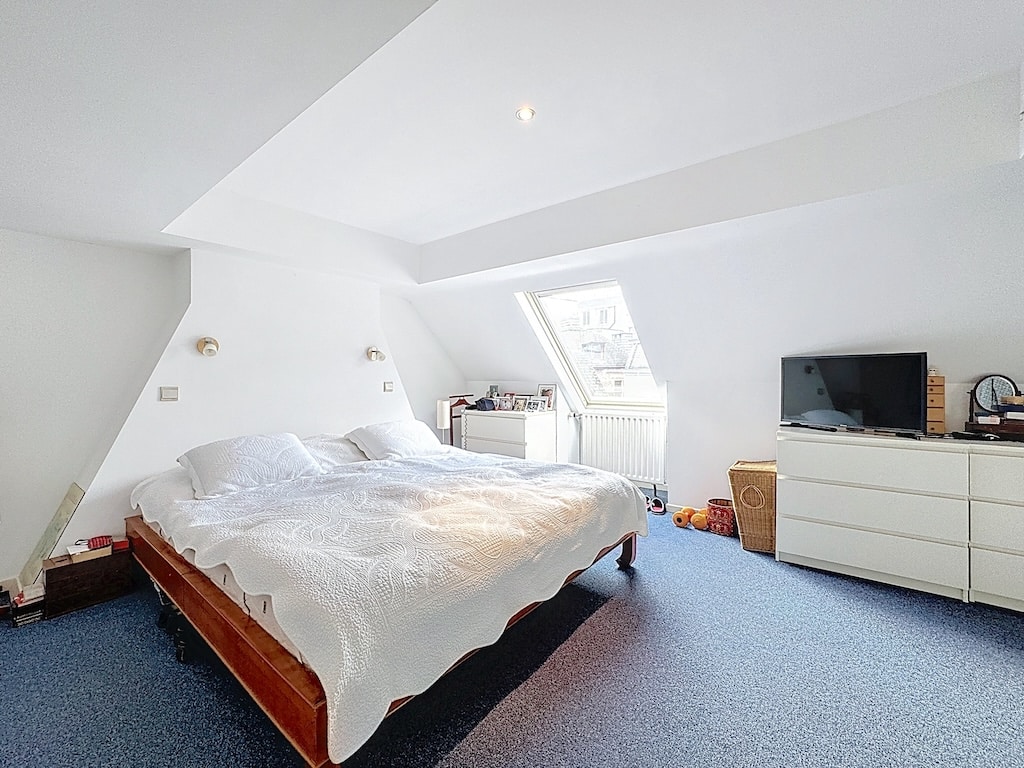 Chambre moderne et cosy avec lit blanc, lumière naturelle, décoration minimaliste, ambiance calmante.