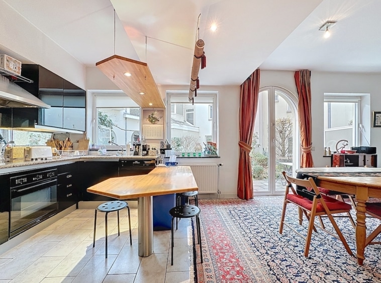 Cuisine moderne épurée avec table en bois organique, coin repas cosy et éclairage naturel.