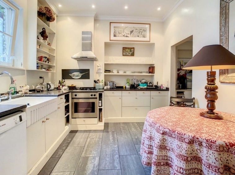 Cuisine moderne chaleureuse, espace repas cosy, plans en pierre sombre, appareils inox intégrés.