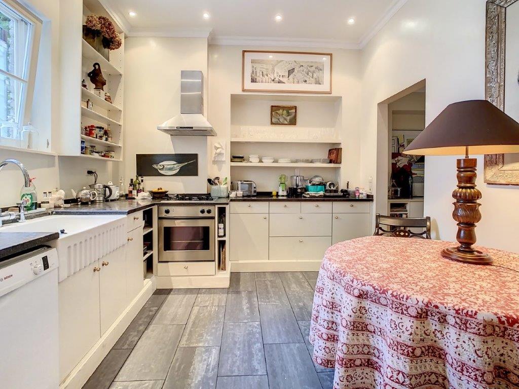 Cuisine moderne chaleureuse, espace repas cosy, plans en pierre sombre, appareils inox intégrés.