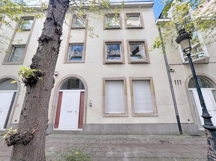 Façade dimmeuble moderne avec arbre ancien, lampadaire vintage, sous ciel clair.