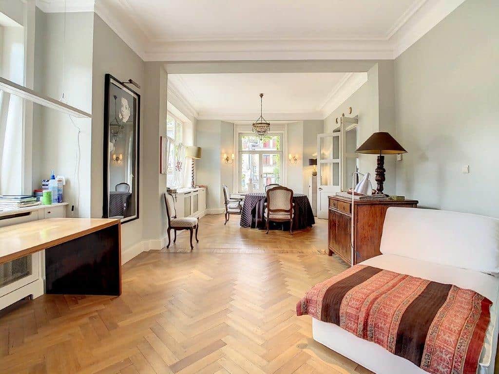 Salon lumineux avec mobilier moderne, murs pastel verts, espace repas cosy, ambiance élégante et chaleureuse.