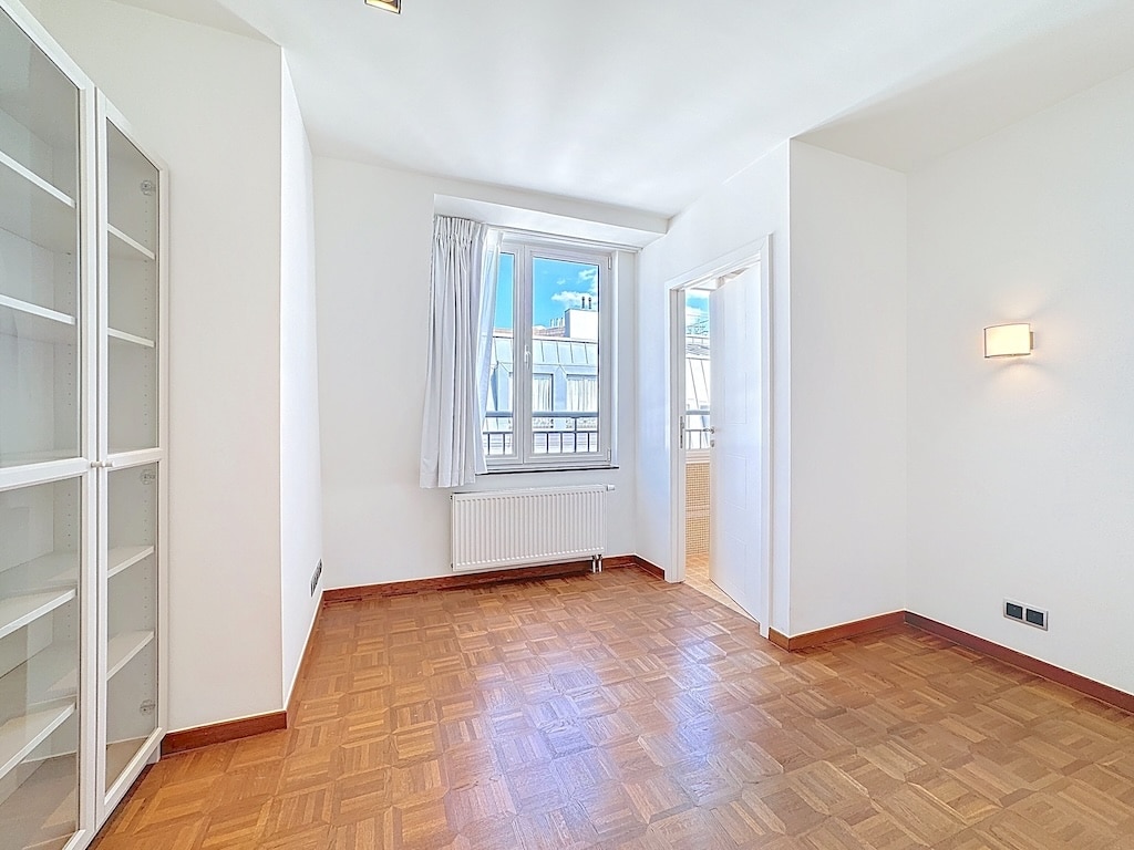 Chambre lumineuse minimaliste avec parquet, étagères, fenêtre, balcon et éclairage moderne.