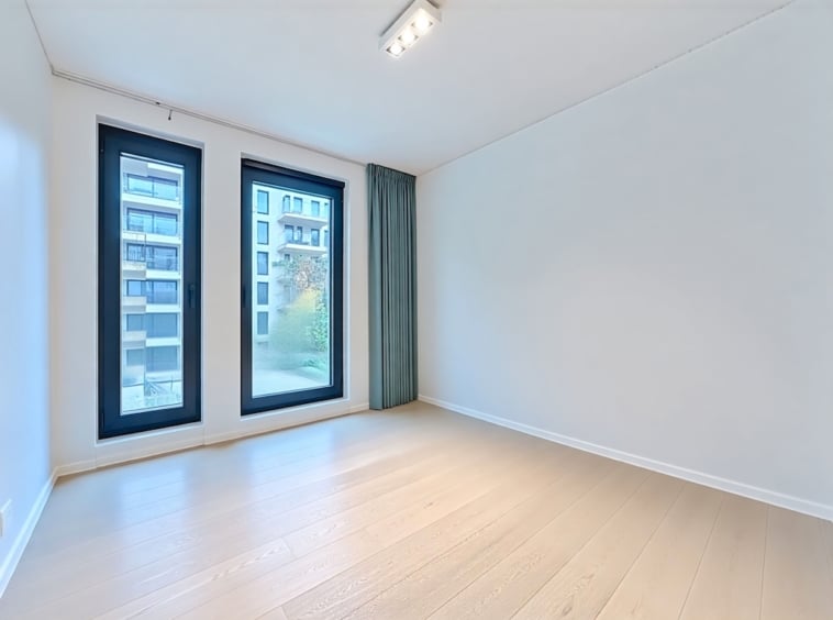 Espace intérieur minimaliste lumineux avec fenêtres panoramiques et décoration moderne en environnement urbain.