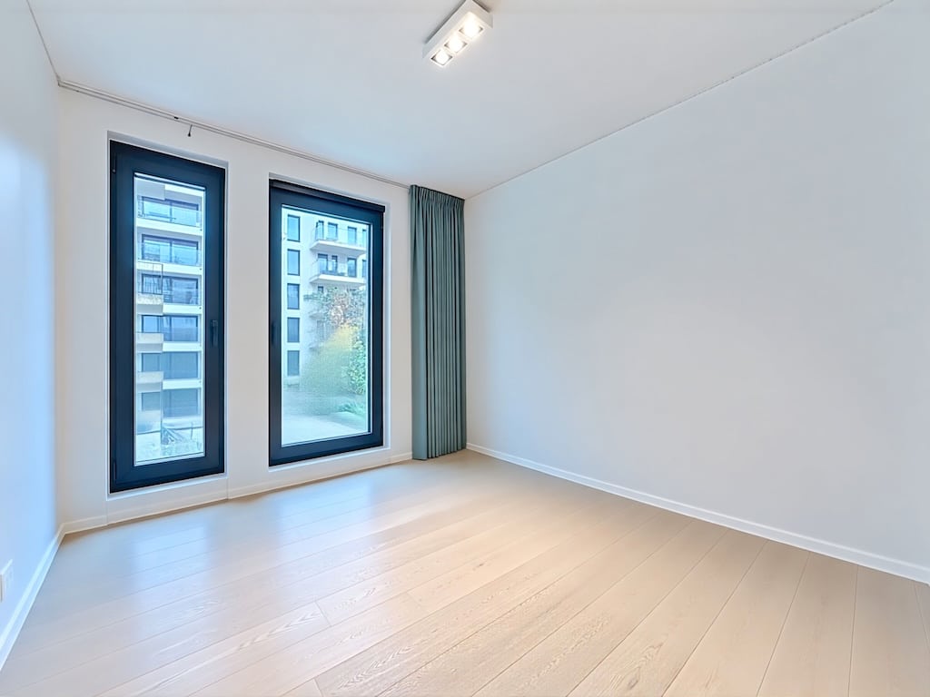 Espace intérieur minimaliste lumineux avec fenêtres panoramiques et décoration moderne en environnement urbain.