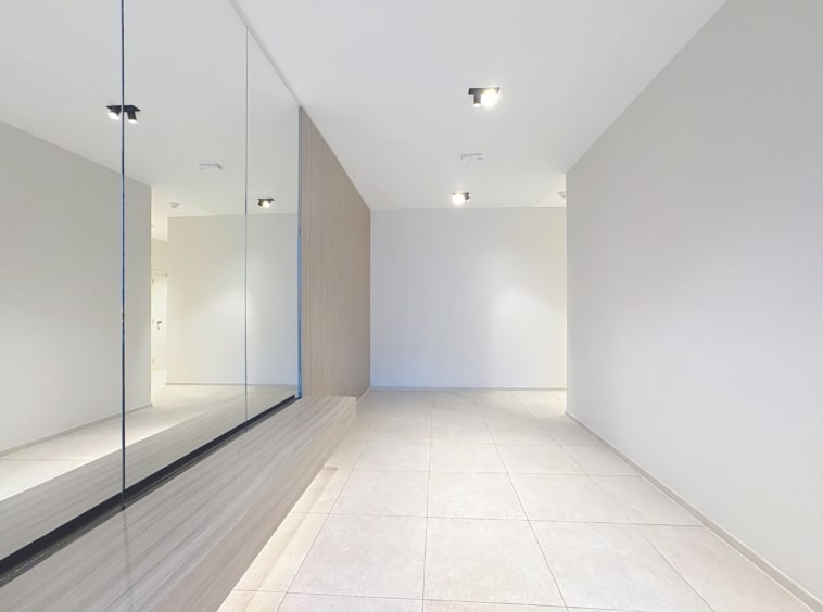 Espace intérieur moderne minimaliste avec miroir, sol clair, éclairage encastré, ambiance lumineuse.