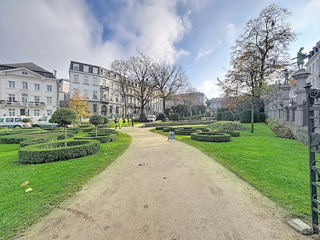 Promenade élégante dans un parc historique, avec sentier de gravier et architecture classique.