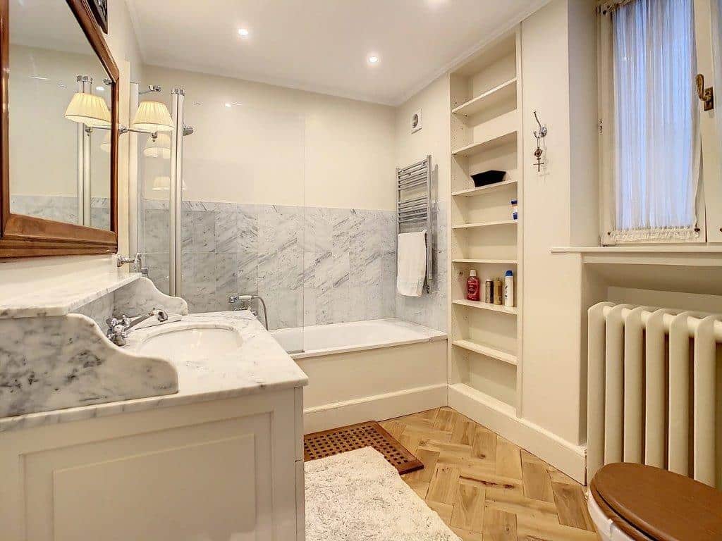 Salle de bain moderne avec marbre, bois, baignoire et mobilier élégant pour une ambiance relaxante.
