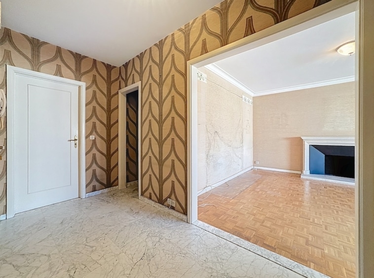 Hall dentrée élégant avec papier peint, sol en marbre et transition vers salle lumineuse.