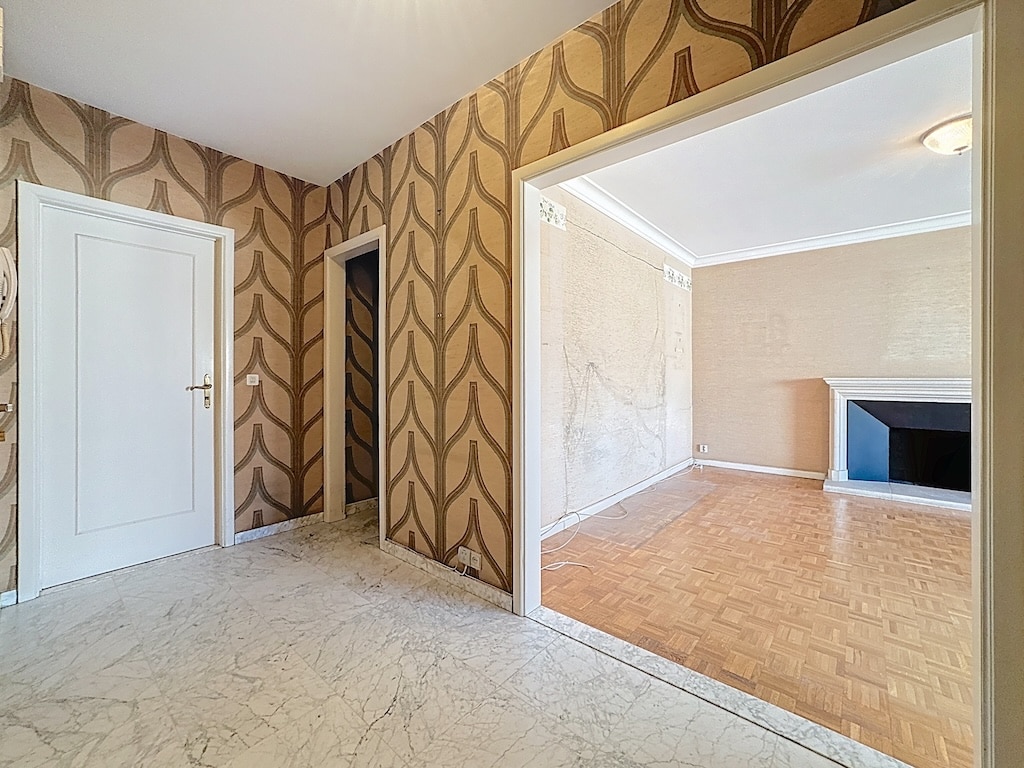 Hall dentrée élégant avec papier peint, sol en marbre et transition vers salle lumineuse.