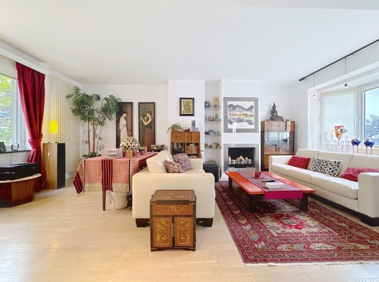 Salon lumineux chic avec canapé coloré, tapis rouge, plantes et coin repas élégant.