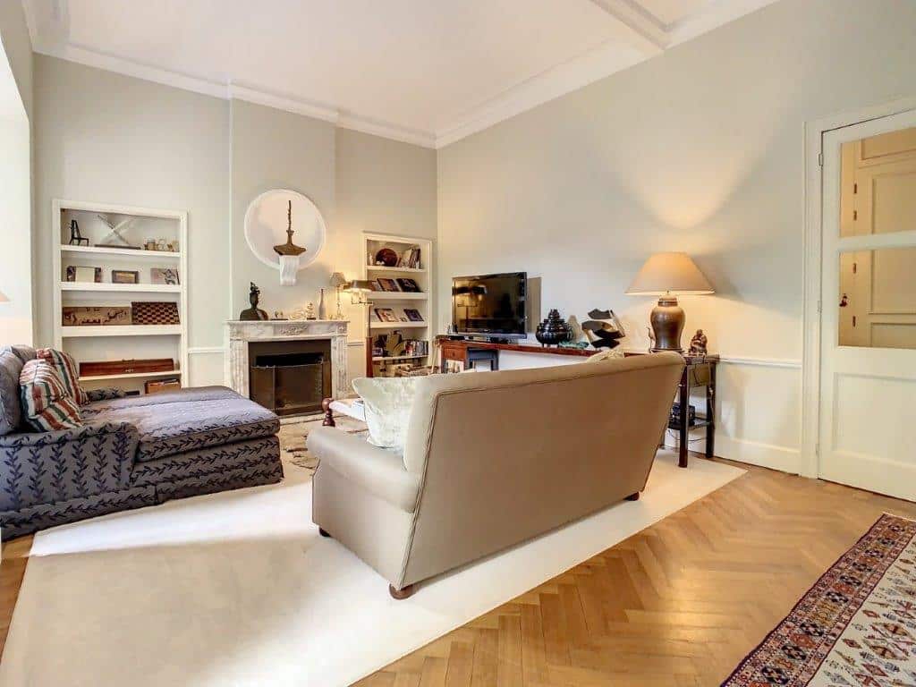 Salon moderne et cosy avec lumière naturelle, parquet, canapé chic et décoration élégante.