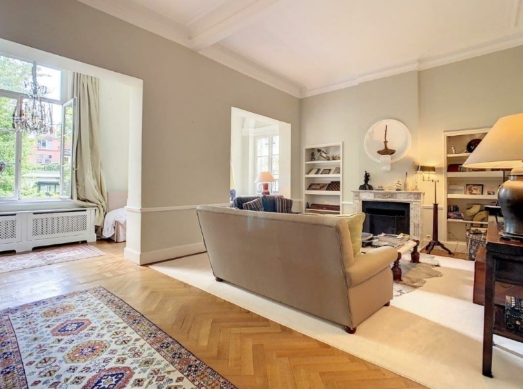 Salon lumineux et cosy avec canapé beige, cheminée, étagère blanche et décor élégant.