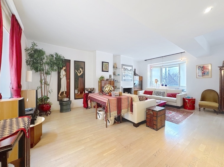 Salon lumineux moderne avec canapé blanc, coussins colorés, plantes et décoration élégante.