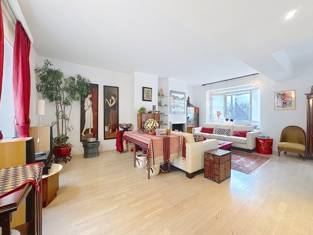 Salon lumineux moderne avec canapé blanc, coussins colorés, plantes et décoration élégante.