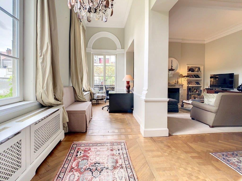 Salon moderne avec espace de travail, canapé cosy, tv, décoration élégante, lumière naturelle abondante.