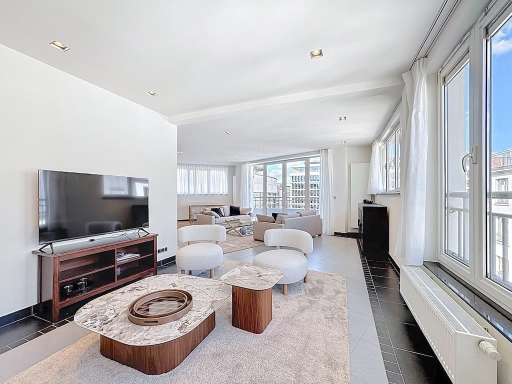 Salon moderne lumineux avec mobilier élégant, grand fenêtres, espace convivial et décoration épurée.