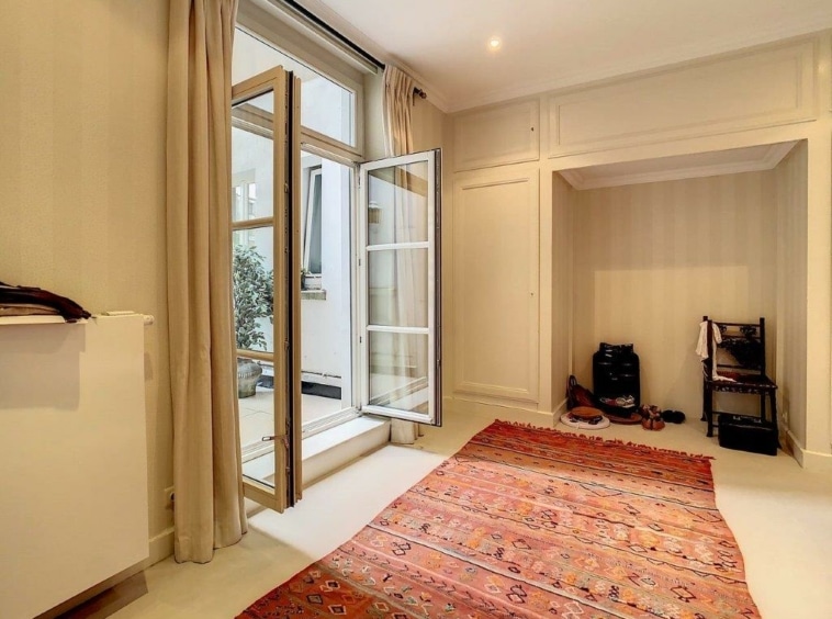 Salon lumineux avec tapis coloré, lumière naturelle, ambiance paisible et décoration minimaliste.