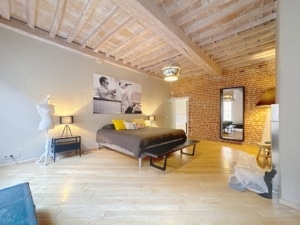 Chambre élégante avec poutres mur en briques lit coloré et décoration minimaliste