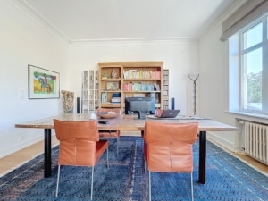 Espace de coworking moderne avec bibliothèque lumineuse, mobilier chic, plantes et décoration élégante.