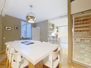 Cuisine moderne lumineuse avec grande table blanche éclairage suspendu et espace convivial