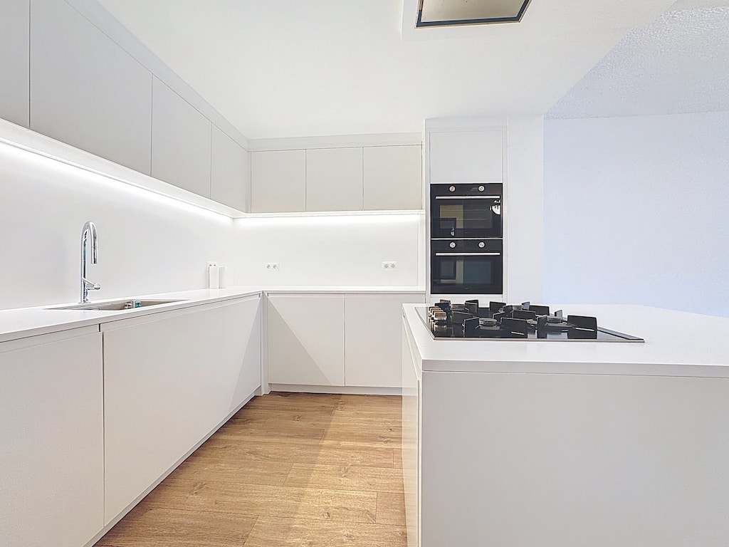 Cuisine moderne minimaliste blanc et bois avec électroménagers encastrés et éclairage discret.