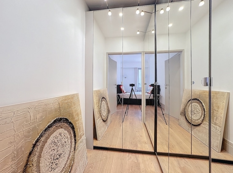 Hall moderne avec miroirs, œuvres abstraites organiques et sol en bois clair.