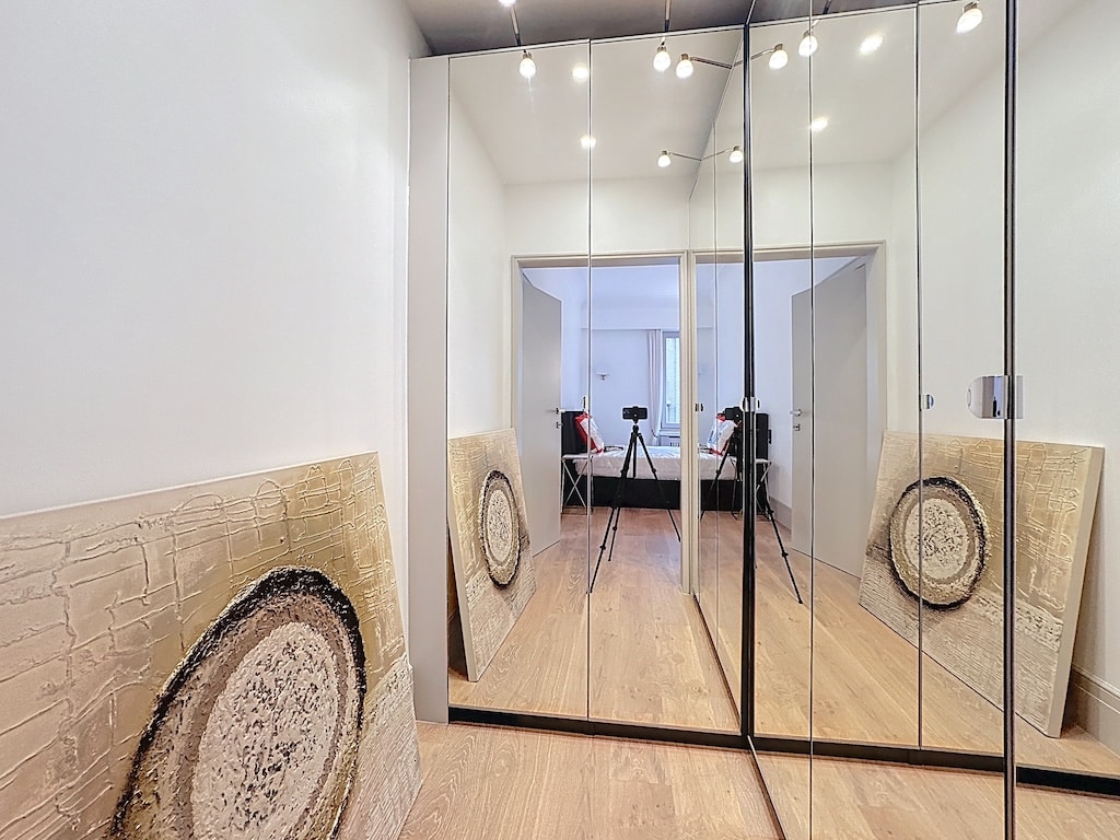 Hall moderne avec miroirs, œuvres abstraites organiques et sol en bois clair.