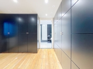 Couloir moderne avec mobilier noir sol en bois clair et porte vitrée lumineuse