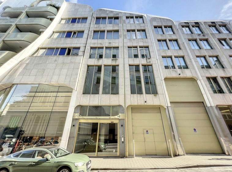 Immeuble commercial moderne avec façade en verre, structure élégante, parking, et design dynamique urbain.