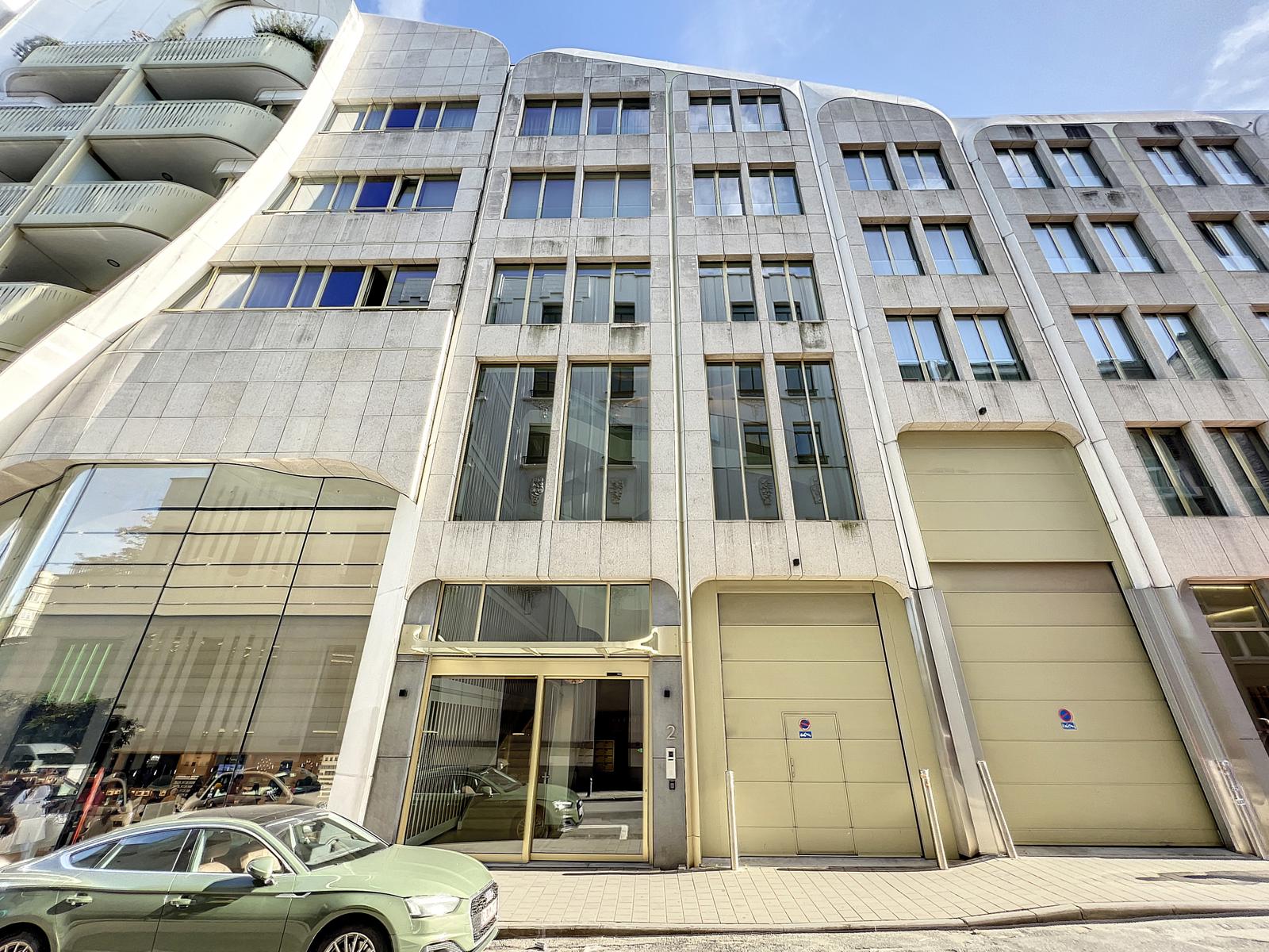 Immeuble commercial moderne avec façade en verre, structure élégante, parking, et design dynamique urbain.