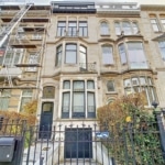 Façade victorienne rénovée avec jardin élégant et échafaudages modernes symbole de patrimoine préservé