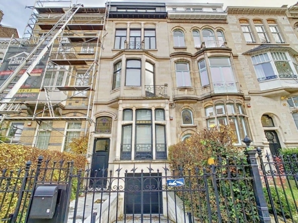 Façade victorienne rénovée avec jardin élégant et échafaudages modernes symbole de patrimoine préservé