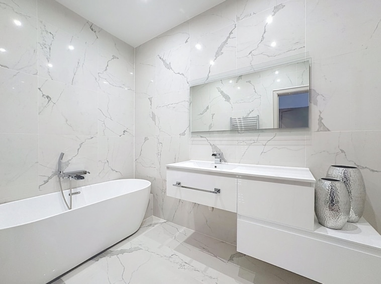 Salle de bain moderne avec baignoire autoportante, miroir grand format, design épuré et élégance.