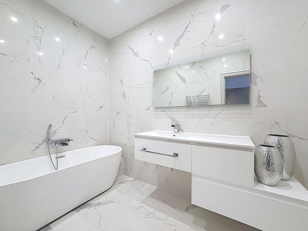 Salle de bain moderne avec baignoire autoportante, miroir grand format, design épuré et élégance.