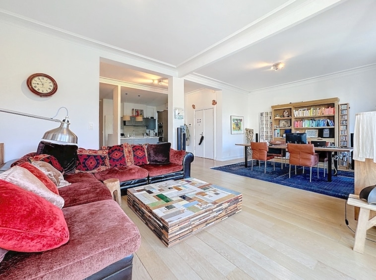 Salon lumineux avec canapé coloré, table en palettes, bibliothèque, espace multifonction, ambiance chaleureuse.