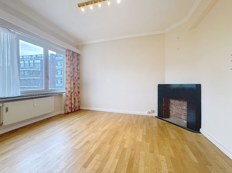 Salon spacieux et lumineux avec cheminée noire, sol en bois clair, ambiance moderne et neutre.