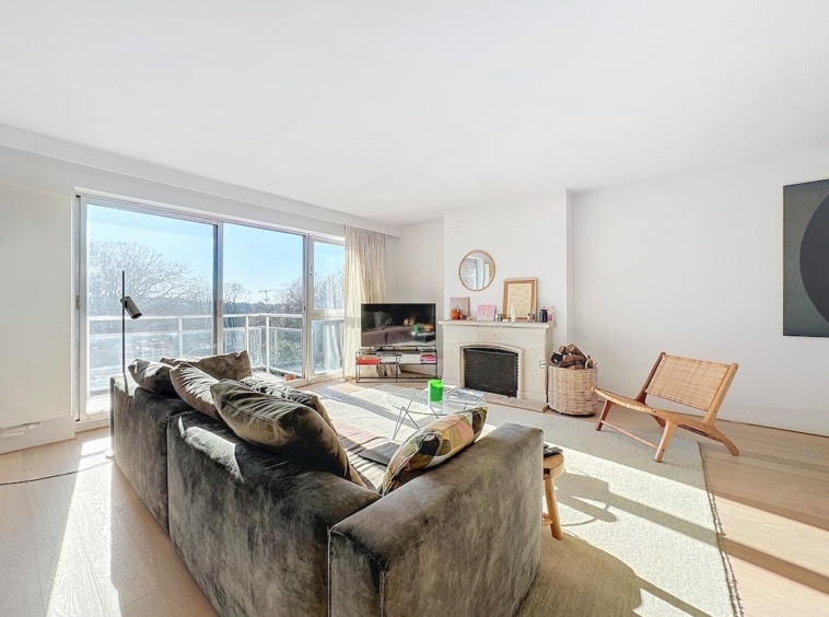 Salon lumineux moderne avec canapé sombre, décoration épurée, cheminée, œuvre géométrique et design minimaliste.