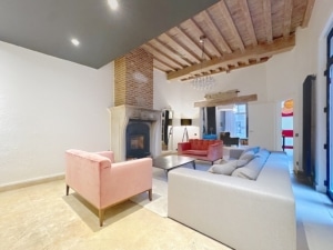 Salon moderne avec cheminée en pierre canapé gris et fauteuil rose en velours ambiance chaleureuse