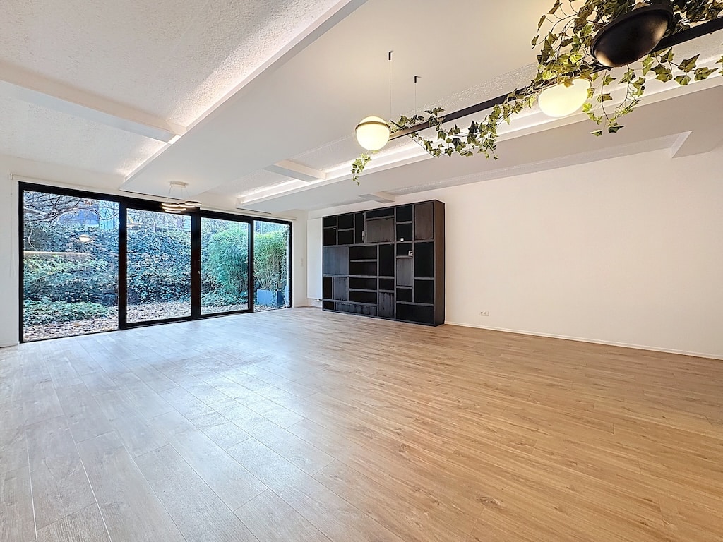 Salon lumineux avec vue sur jardin, plancher en bois clair, décoration moderne et naturelle.