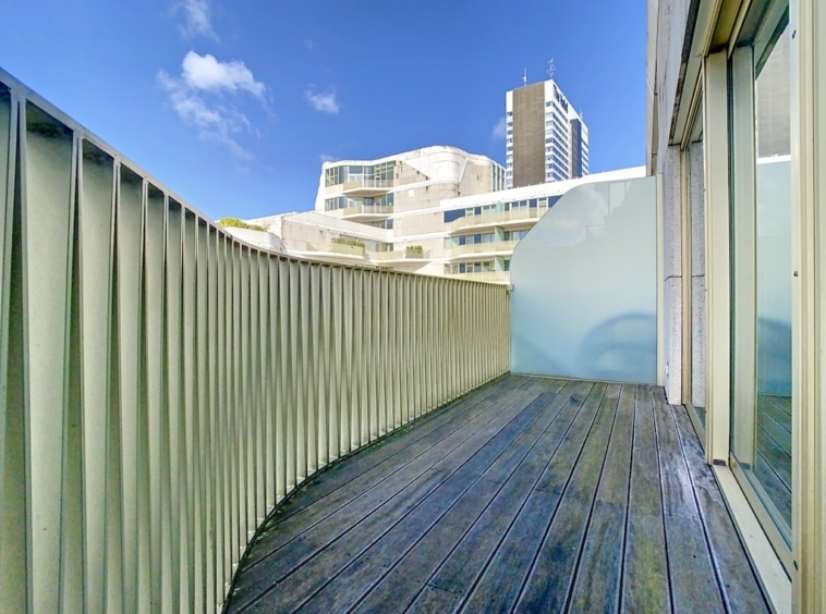 Balcon design moderne avec vue urbaine, balustrades ondulées en bois, ambiance lumineuse et apaisante.