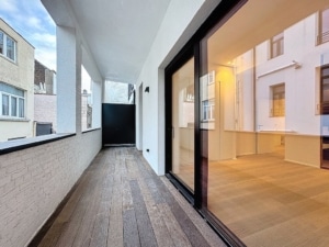 Balcon moderne lumineux avec sol en bois grandes fenêtres vitrées idéal pour détente et vie urbaine