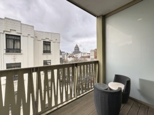 Balcon contemporain avec vue urbaine mobilier en rotin architecture mixte et ciel nuageux