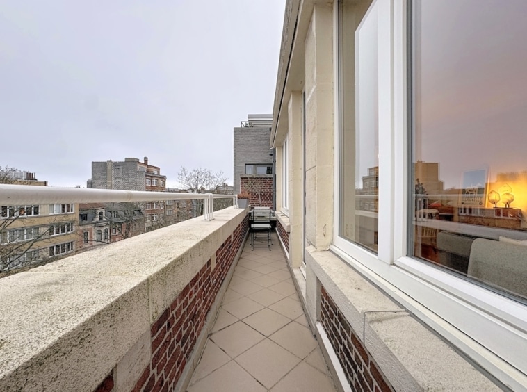 Balcon urbain moderne avec vue sur la ville, fauteuil minimaliste et ambiance tranquille.